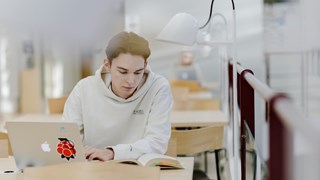 Studenten Hugo pluggar med dator och anteckningsblock.